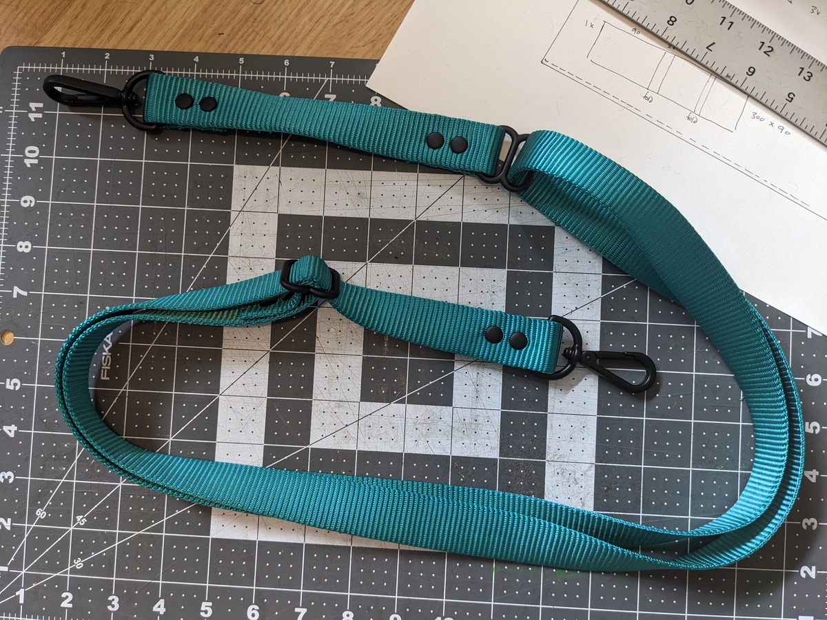 A nylon webbing shoulder strap in bright teal with clips on each end.