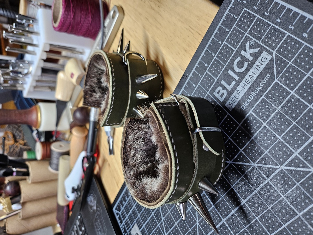 Olive green leather cuffs with silver spikes and a shearling lining.