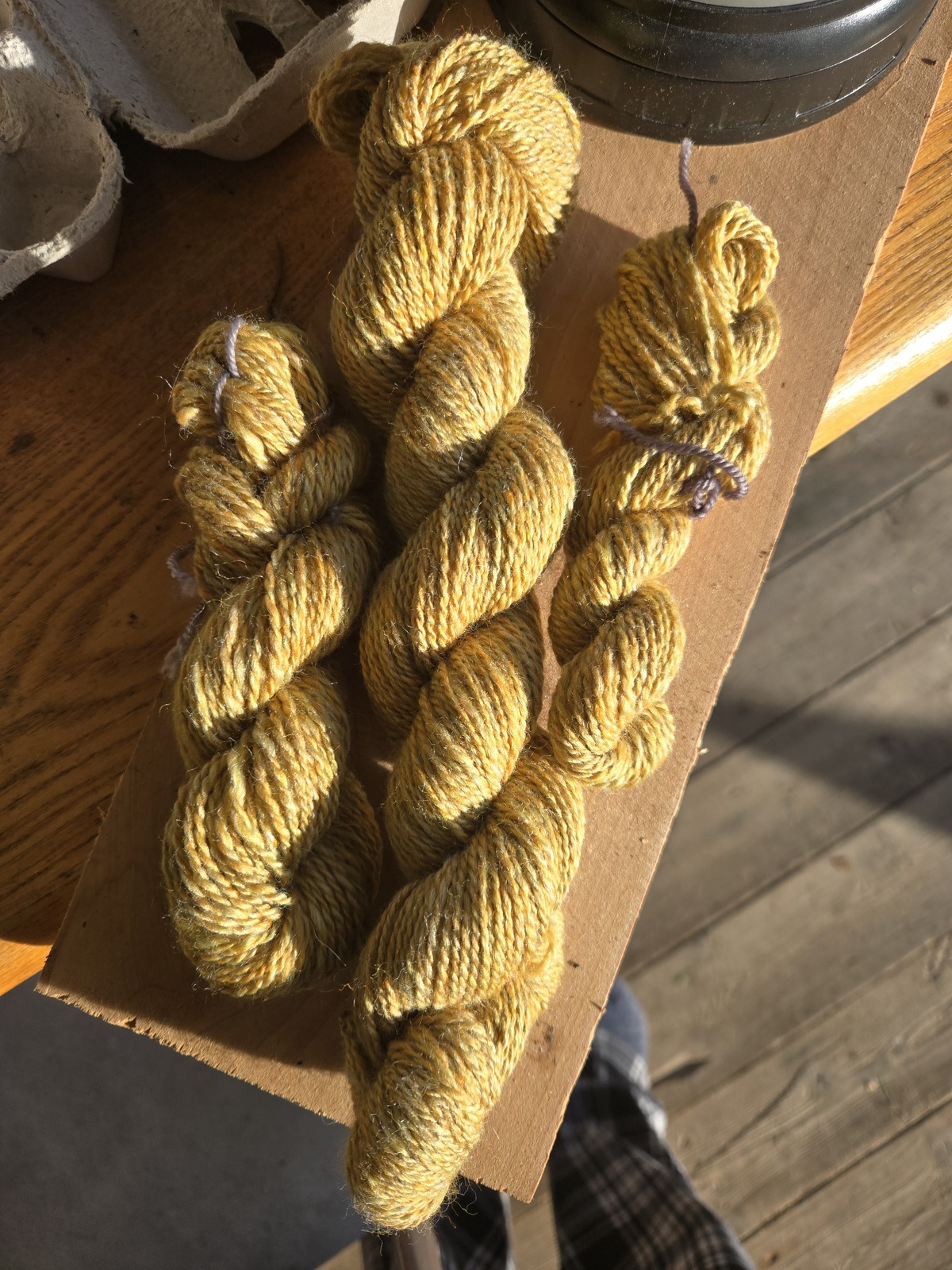 3 skeins of handspun yarn, 1 large and 2 small. One of the small skeins is a little more inconsistent weight than the other two - this one was spun on drop spindle about 2 years ago. The other two are about a sport or maybe a DK weight. All three are a gold colorway with tiny hints of orange and a pale light green.