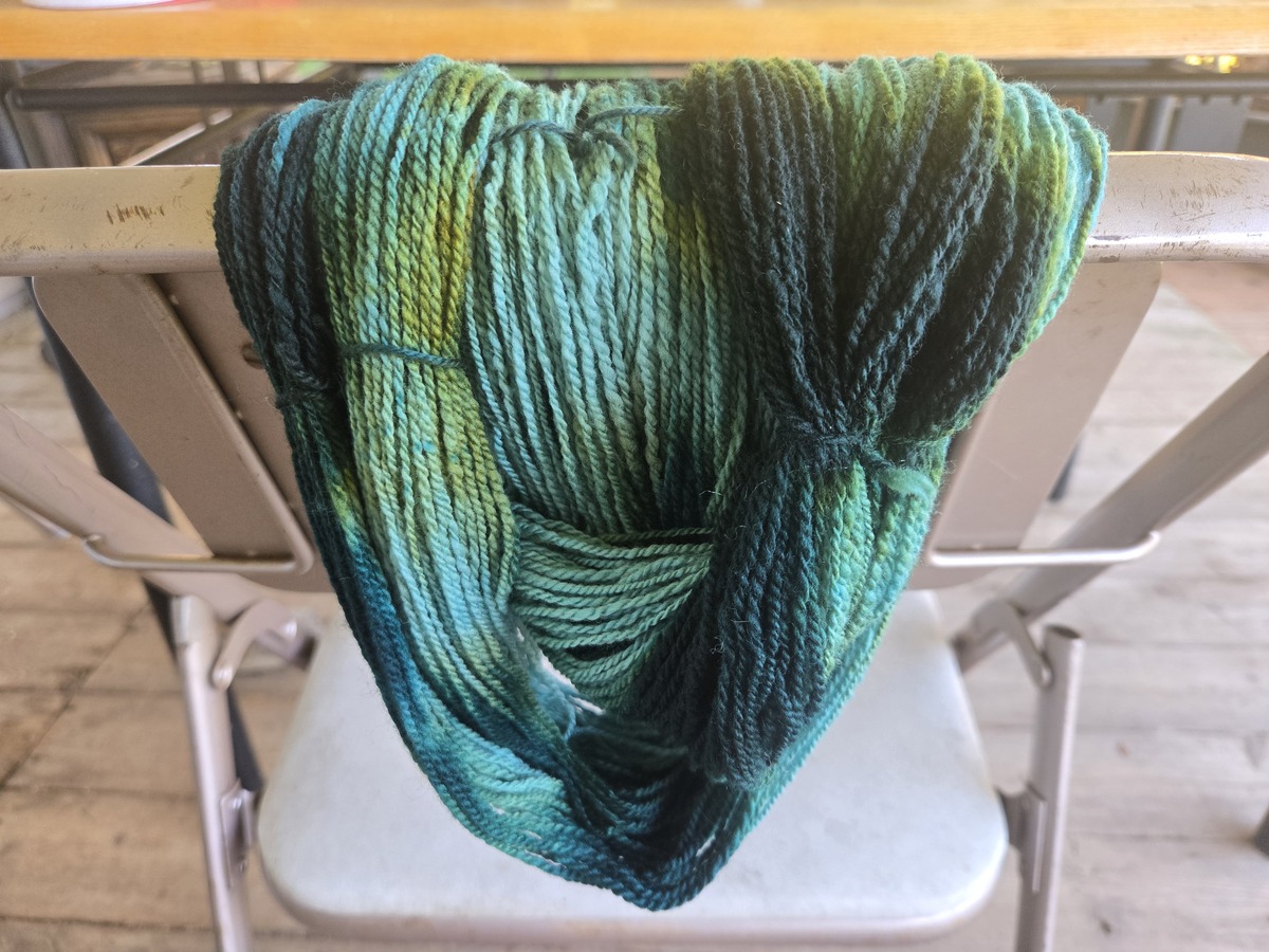 loose loops of yarn that has been dyed a teal and green blend in many shades and tints.