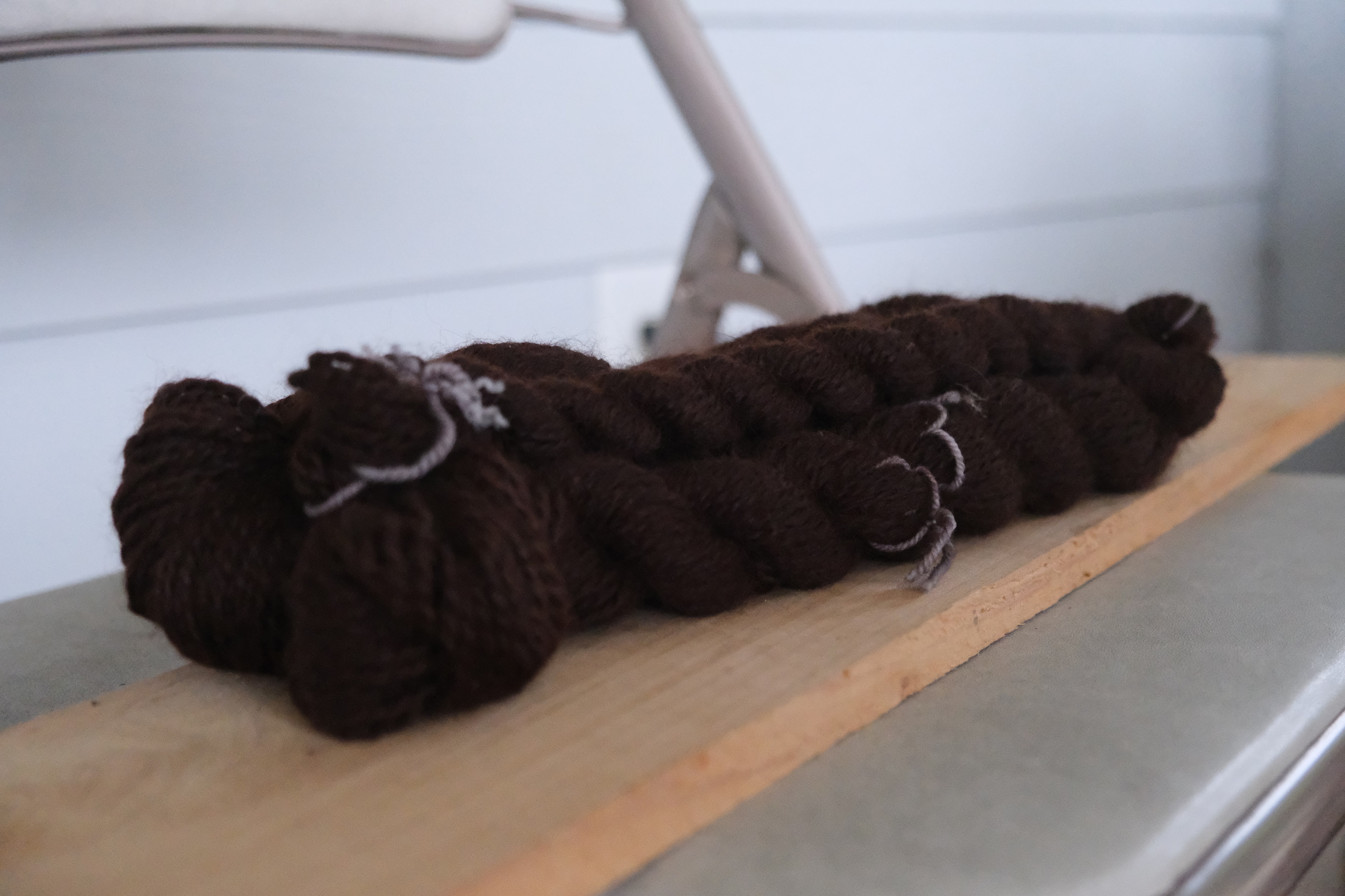 one large skein and two smaller skeins of a rich chocolatey brown alpaca handspun, in about a DK weight