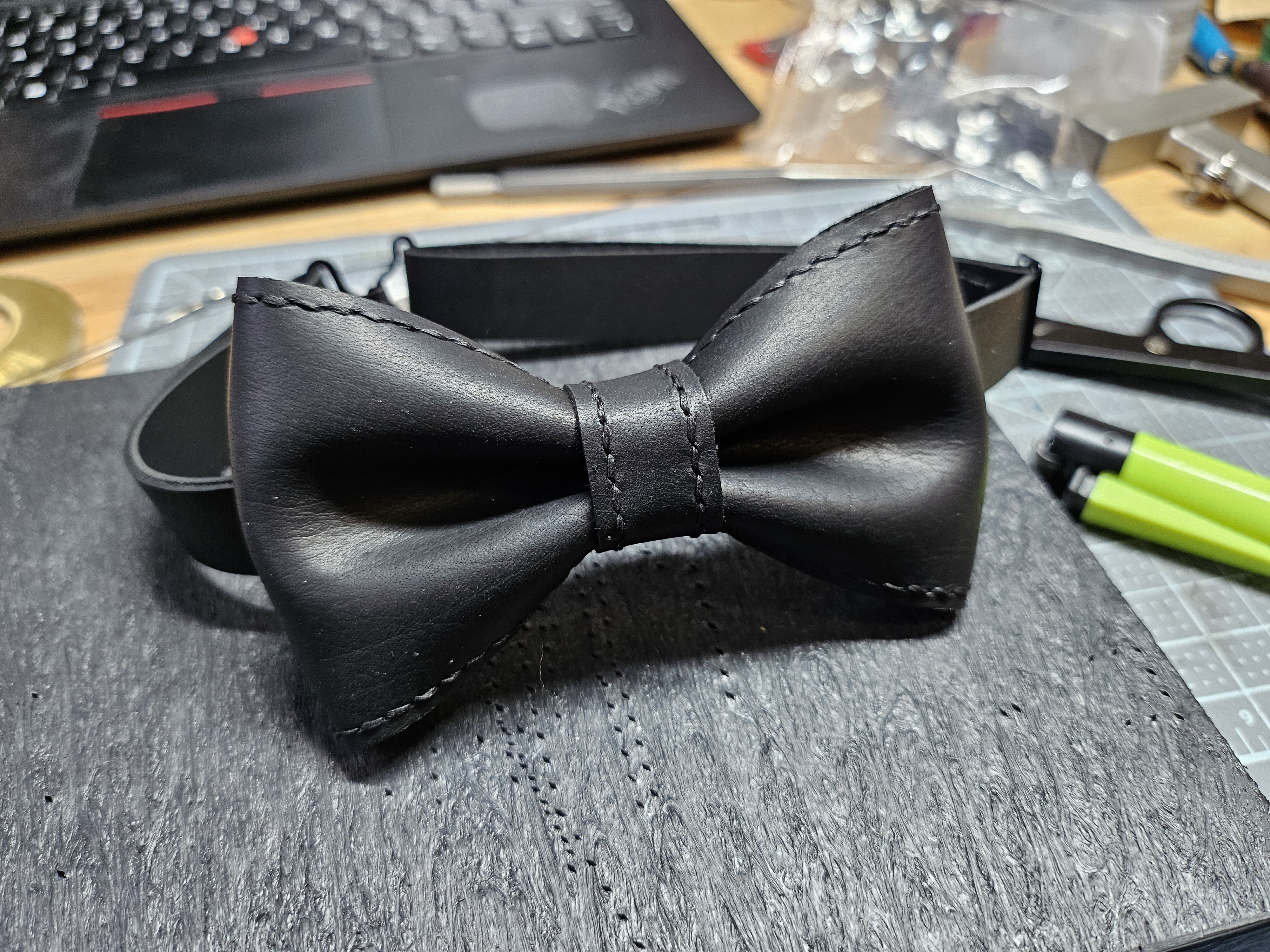 A black leather bow tie with black stitching.
