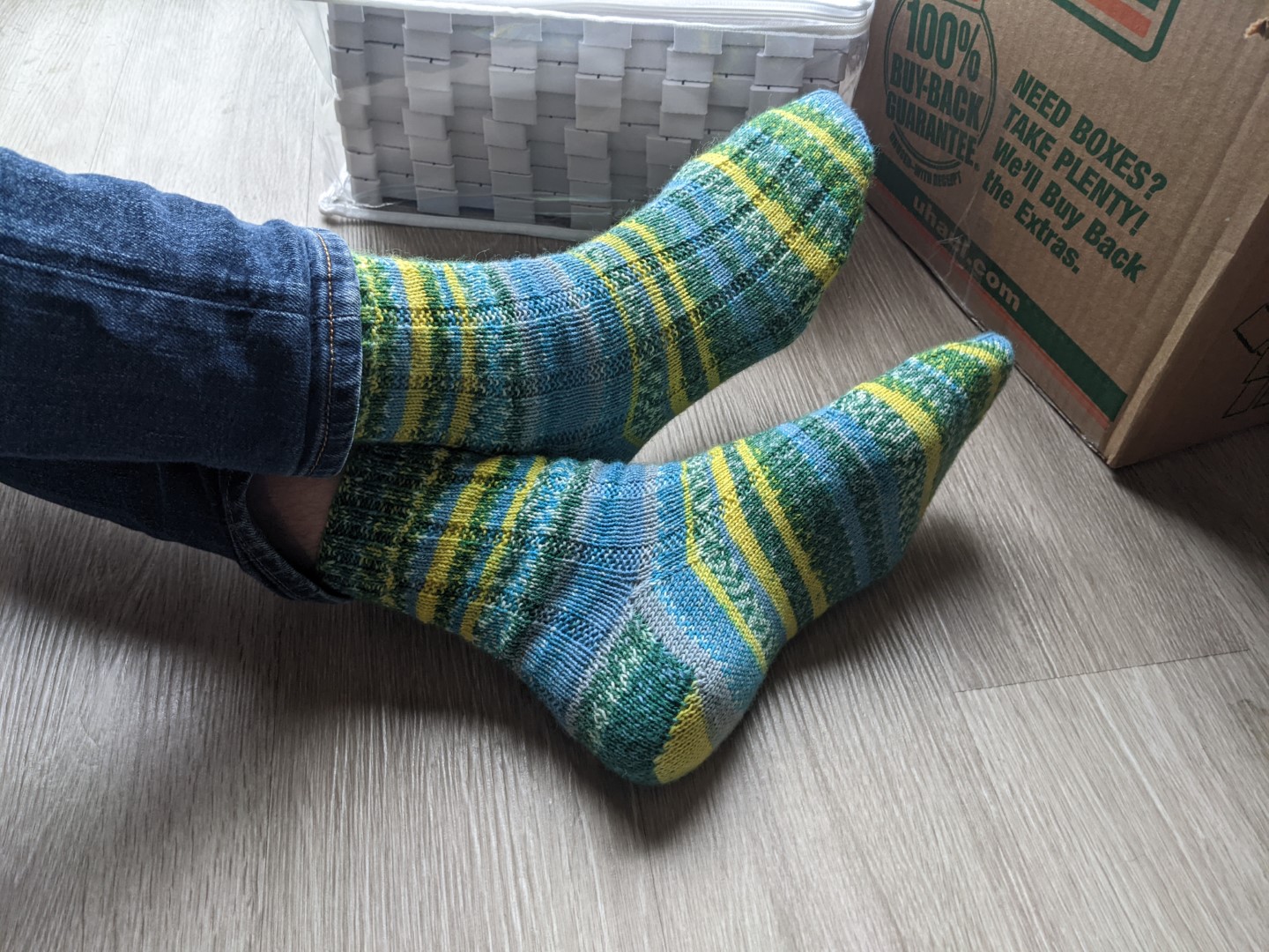 Feet in a pair of colorful socks. They are identically striped and quickly vary between yellow, green, blue, white, and gray.