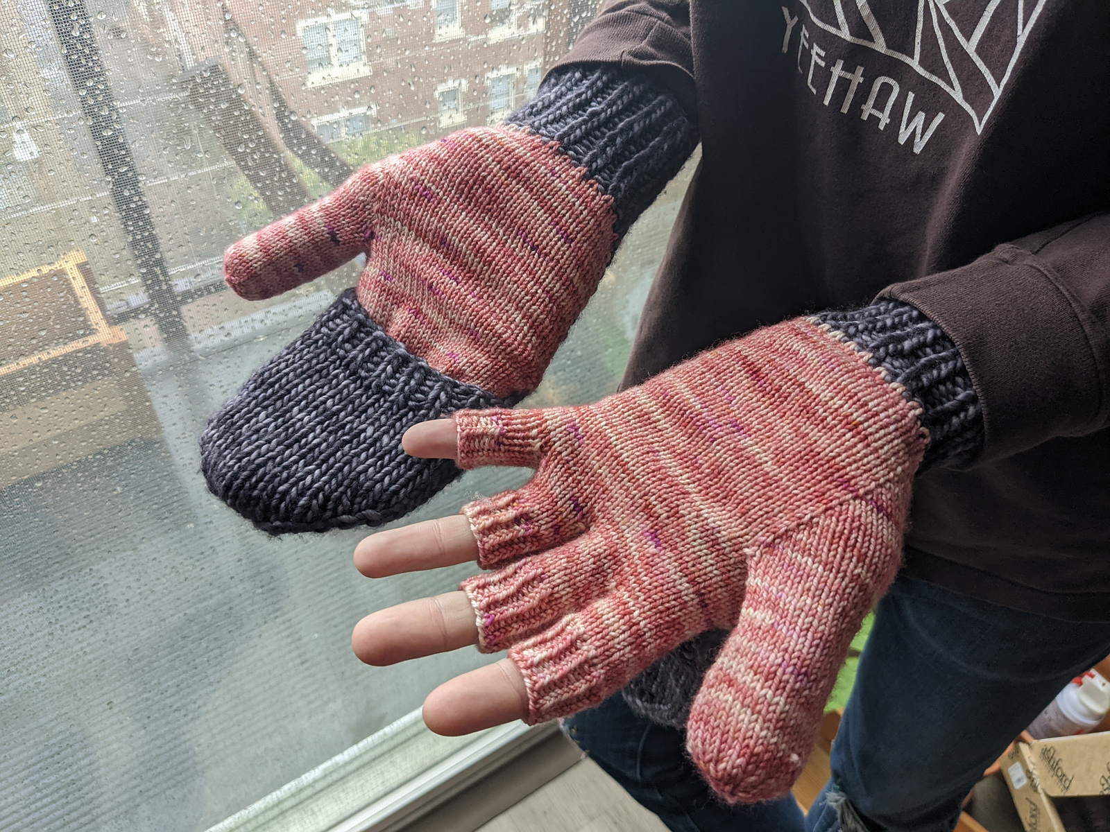 Hands wearing a pair of pink and grey gloves with convertable mitten tops.