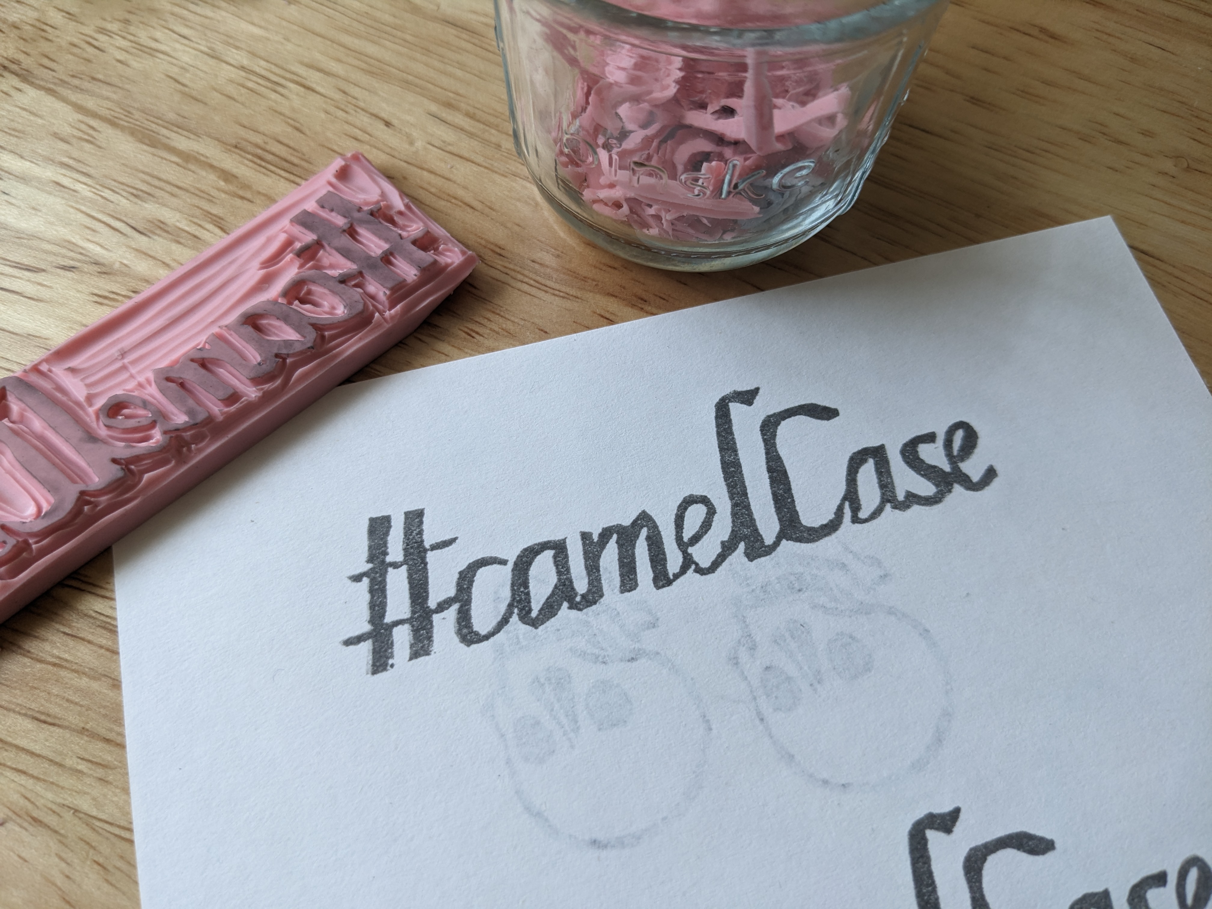 A carved stamp next to its print. The print reads '#camelCase' in a slightly formal-looking italic font.