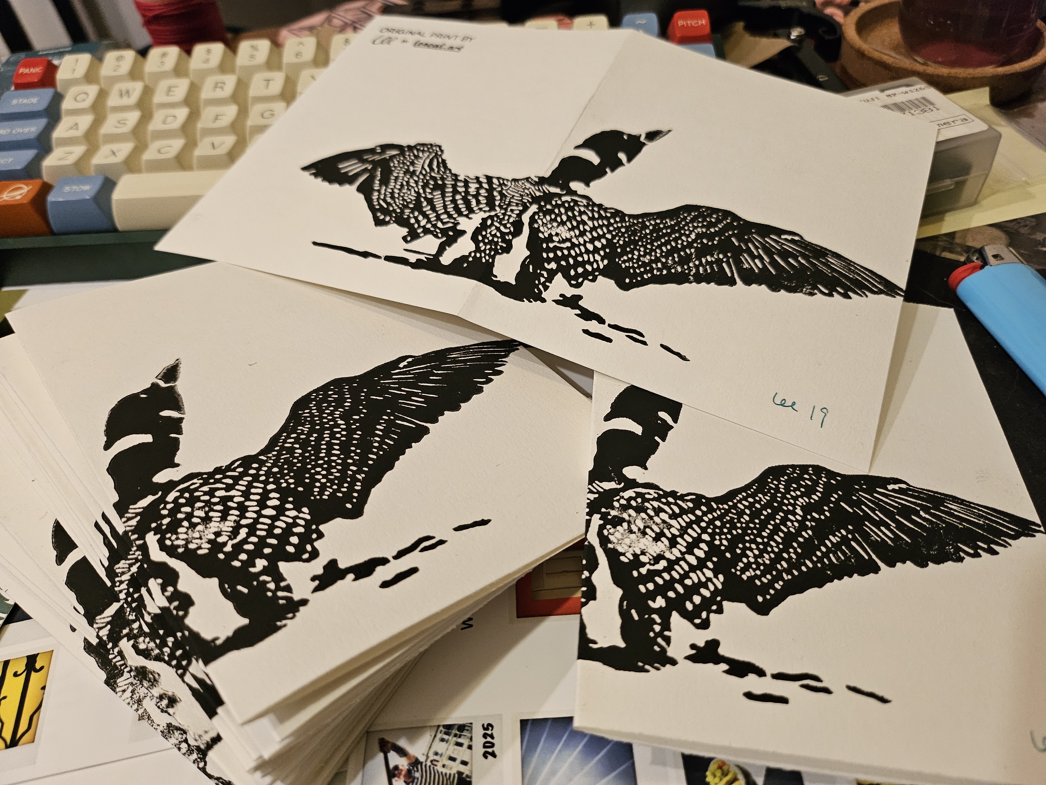 A pile of hand-printed A2 size greeting cards. A loon rearing up with outstretched wings spans the front and back of the cards.