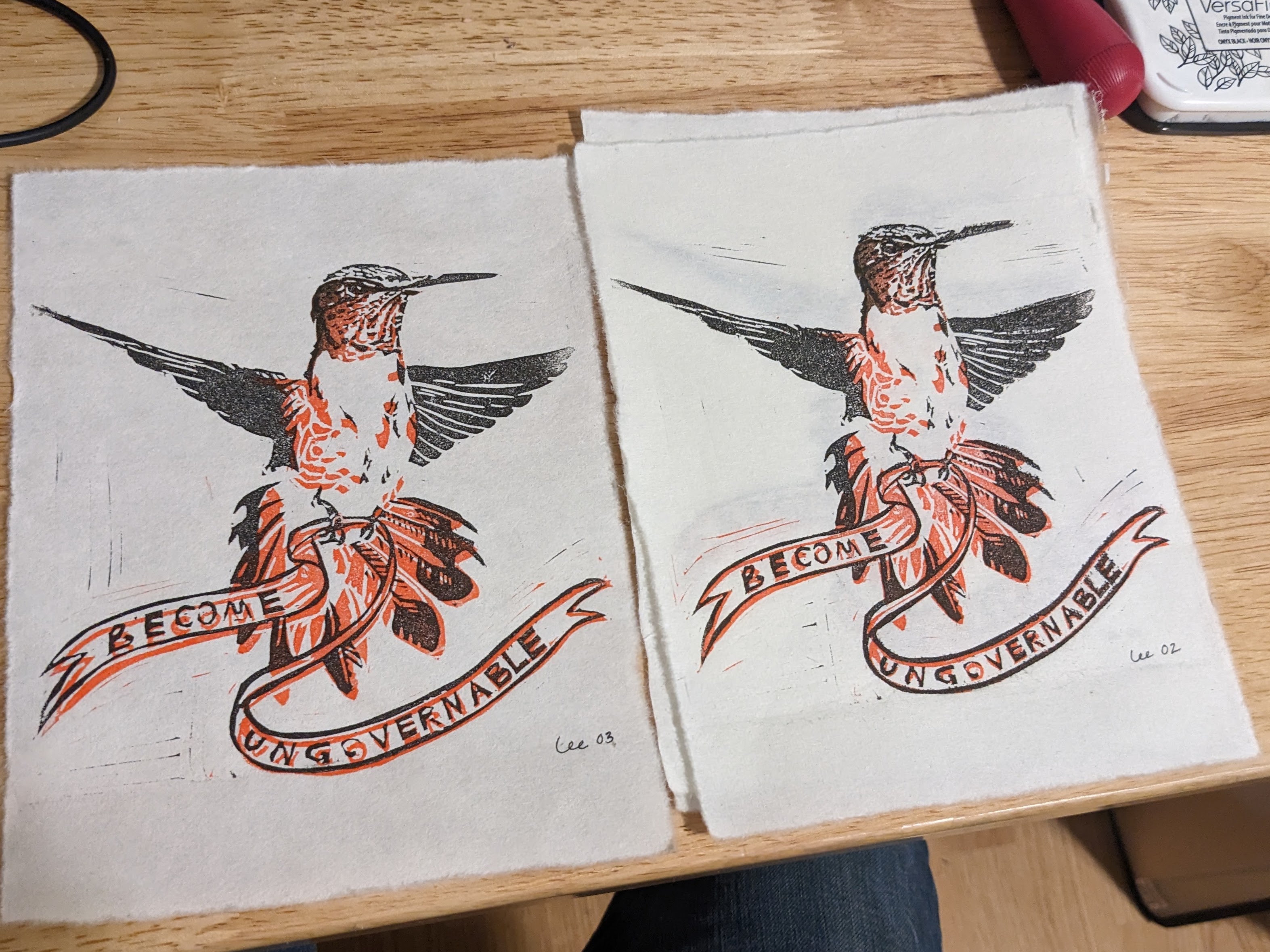 A block print in black and orange ink of a rufous hummingbird, tail flared, hovering in midair. Clutched in eir tiny claws is a banner that waves in the wind and reads 'become ungovernable'