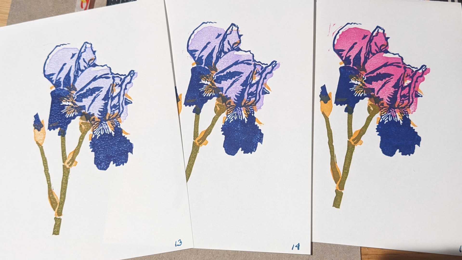 3 copies of the same print of iris flowers and a bud, done in slightly varied color schemes.