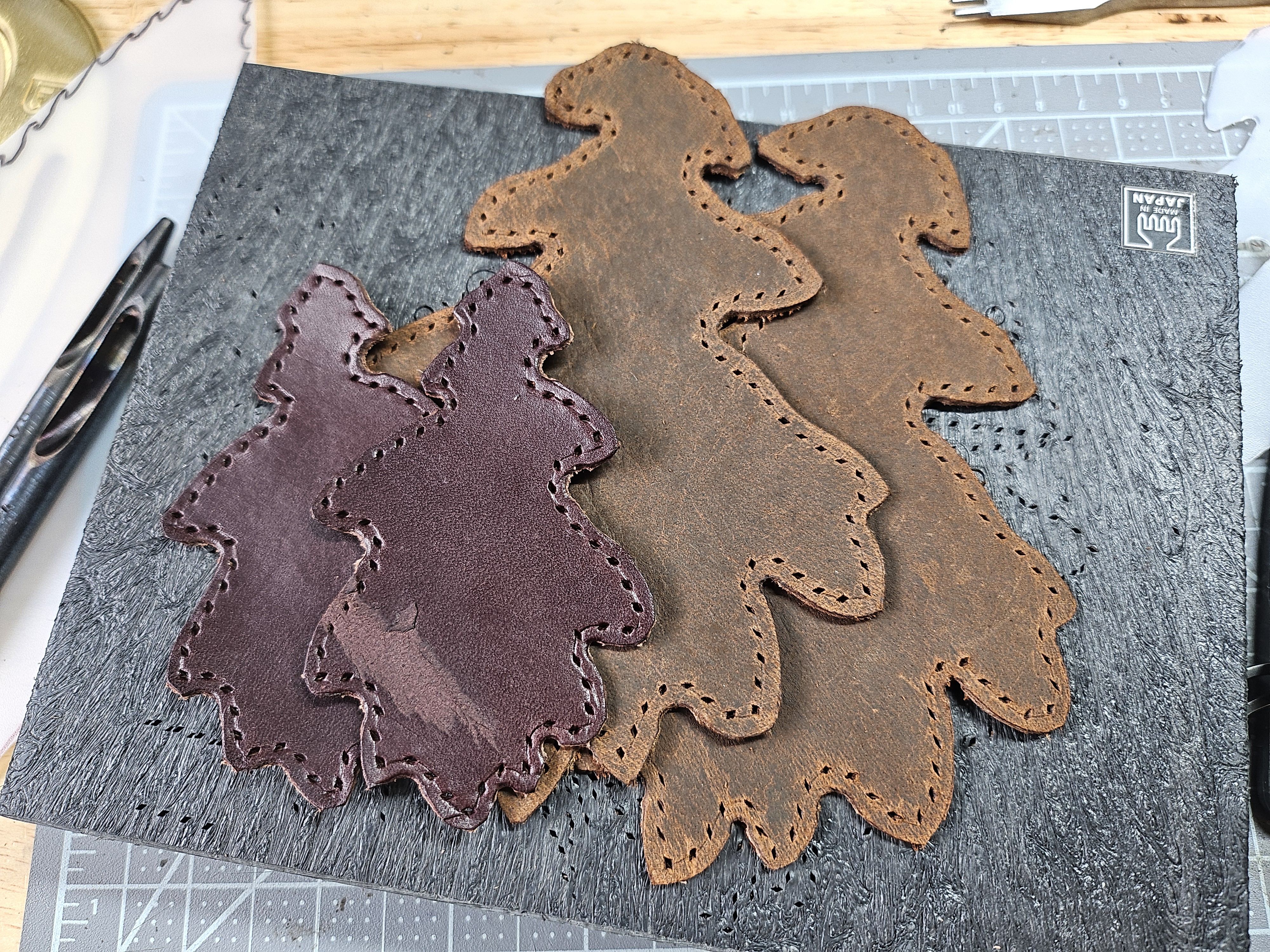 Several oak-leaf-shaped leather patches with stitching holes punched around the edges.