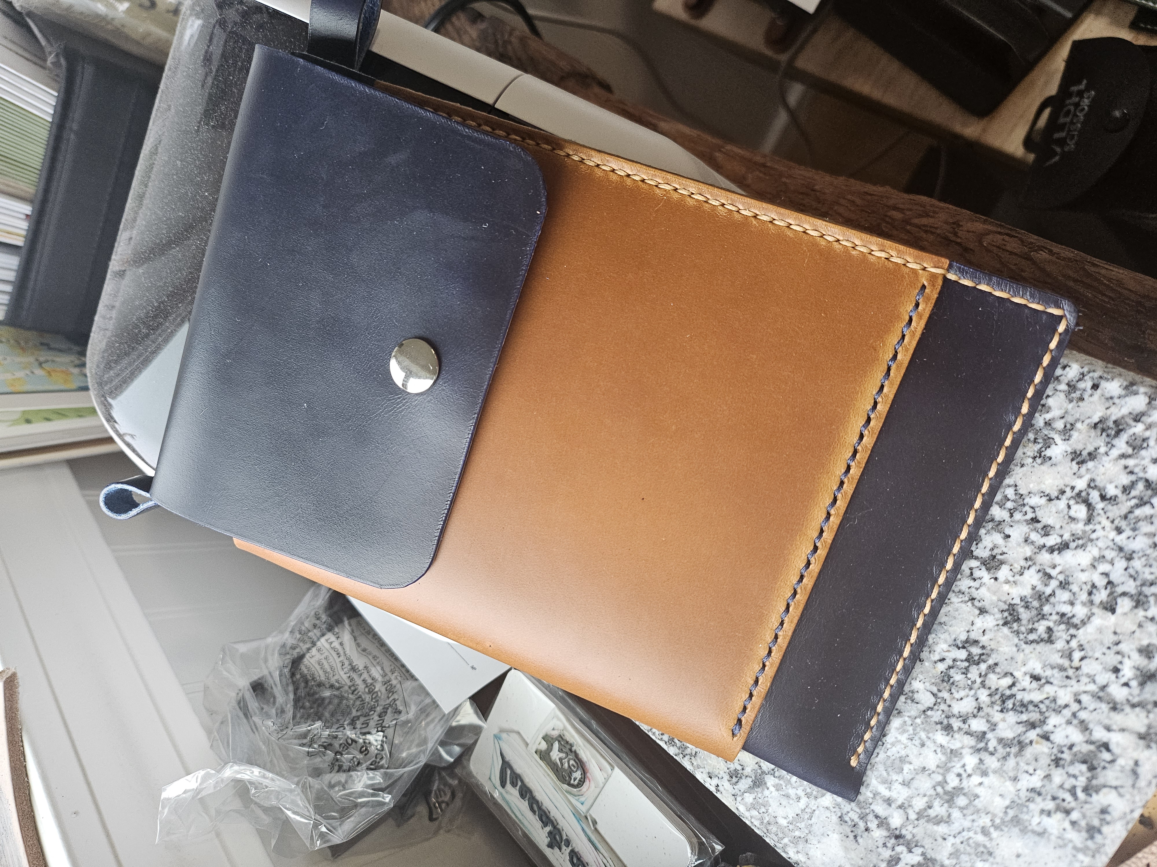 A leather bag sized for a large smartphone with a main pocket and a wraparound smaller pocket. It has a magnetic clasp.