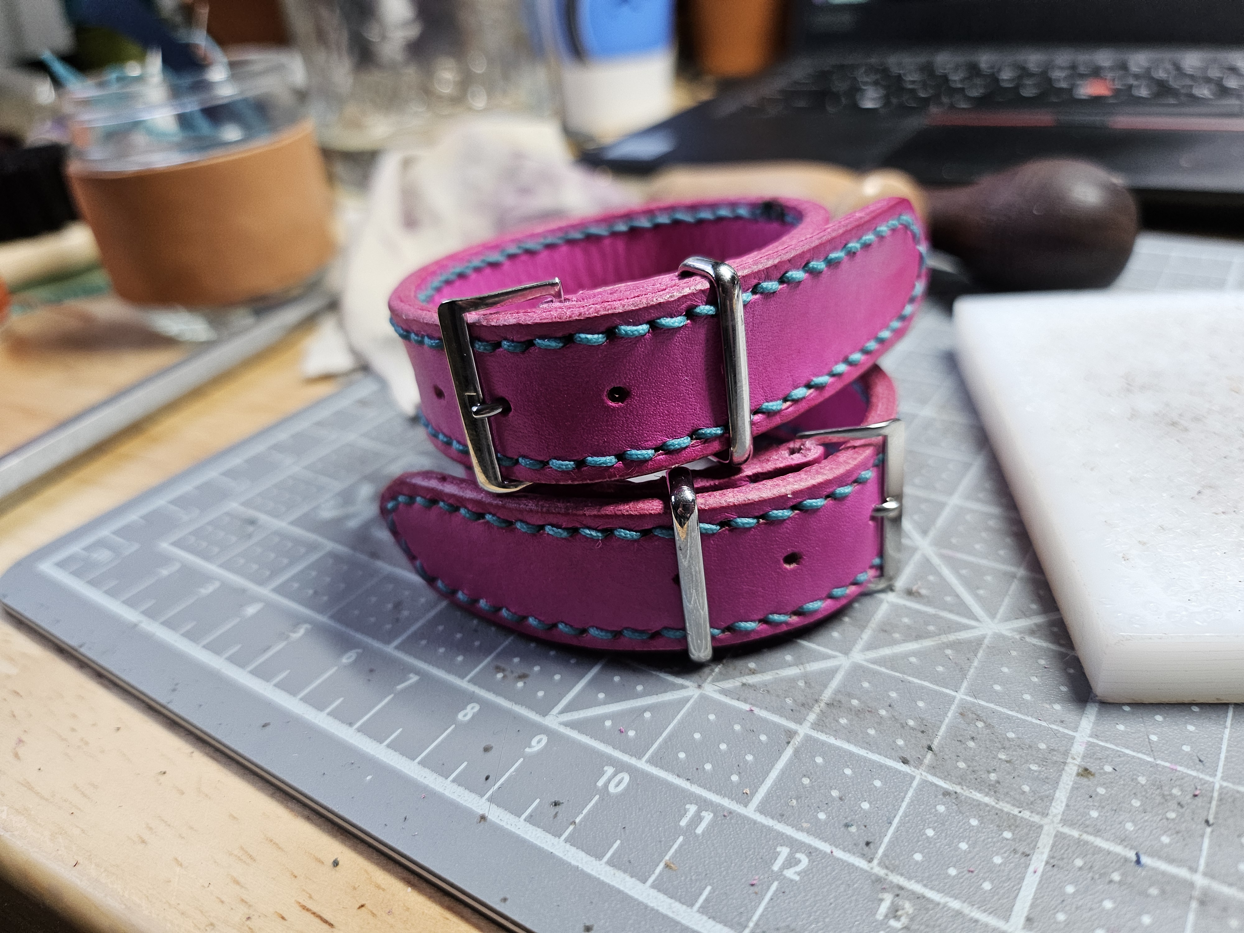 Two pink leather bracelets with stainless steel hardware and aqua stitching.