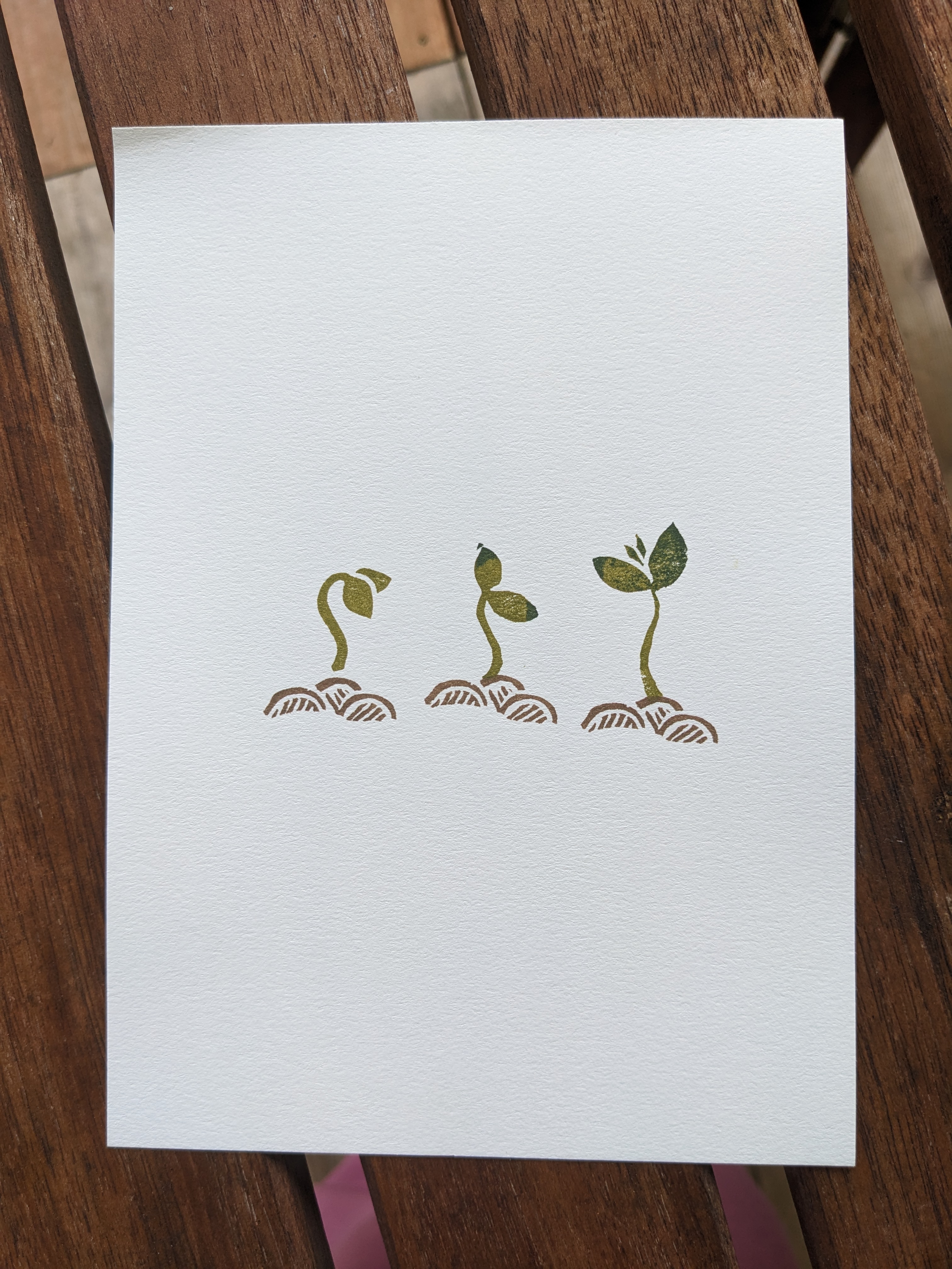 A print of a 3-stage design of a green seedling barely open, starting to straighten up, and growing strong, with little piles of dirt beneath each one.
