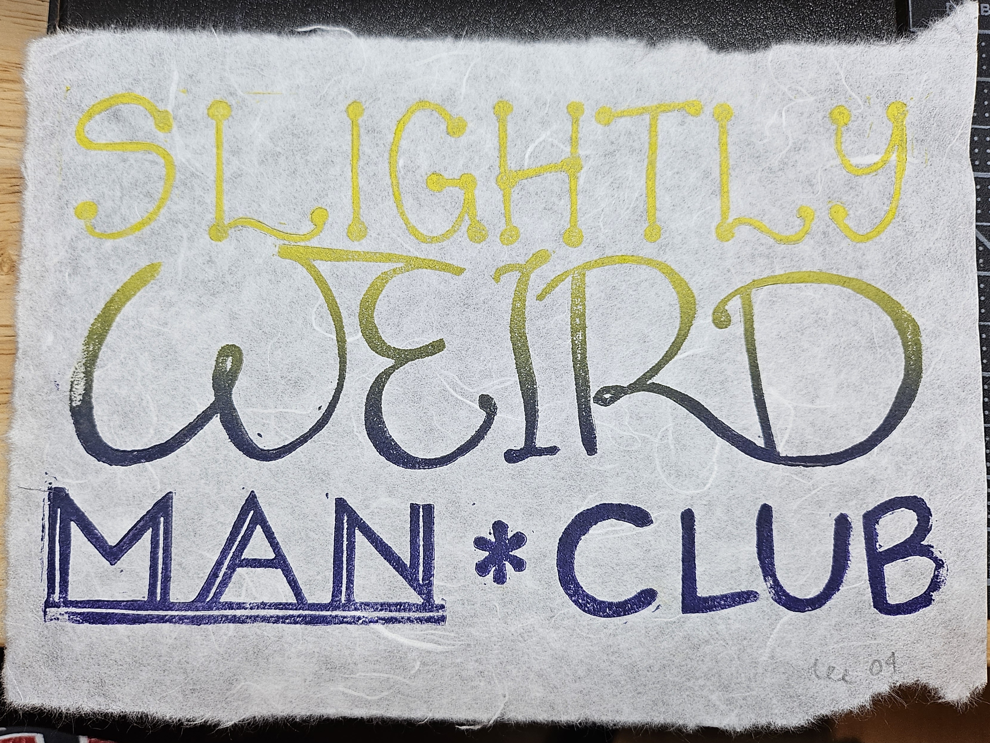 A print that reads 'slightly weird man club' in a nonbinary flag colored gradient