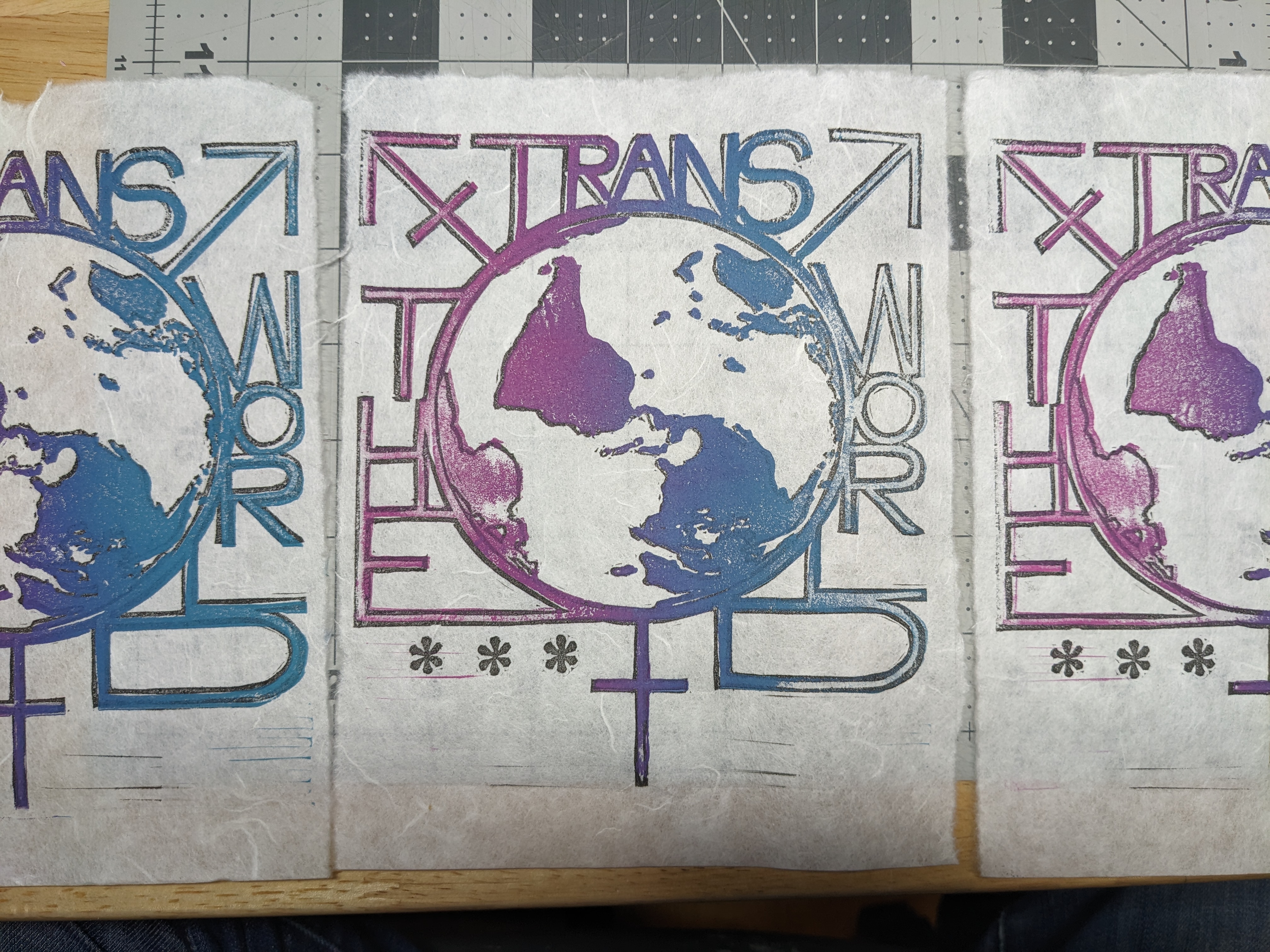 A print that reads 'trans the world' surrounding an image of a globe and a trans symbol. It's in a ping-to-blue gradient.