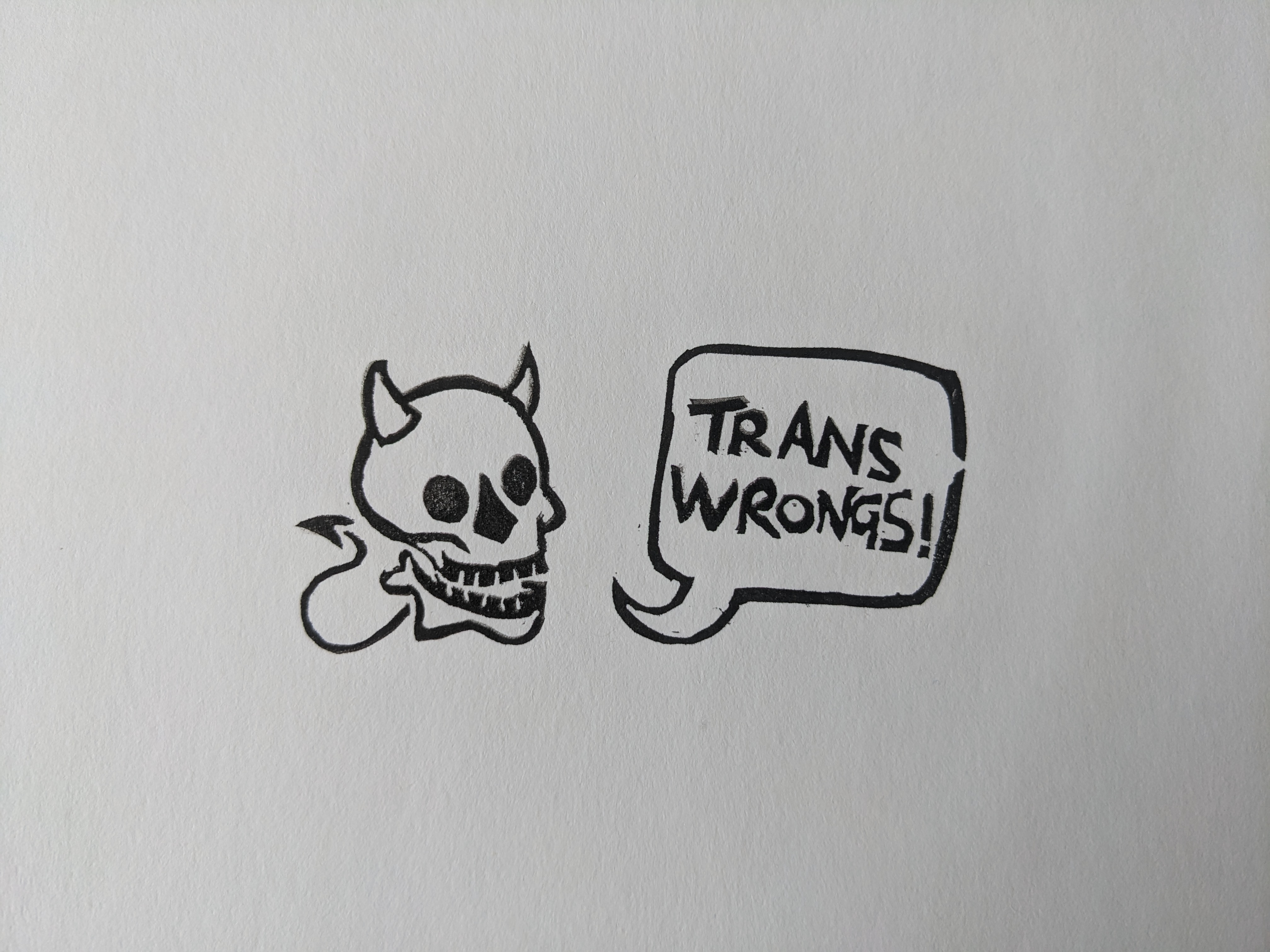 A smiling skull with devil horns and a little spiked tail, and a speech bubble reading 'trans wrongs!'
