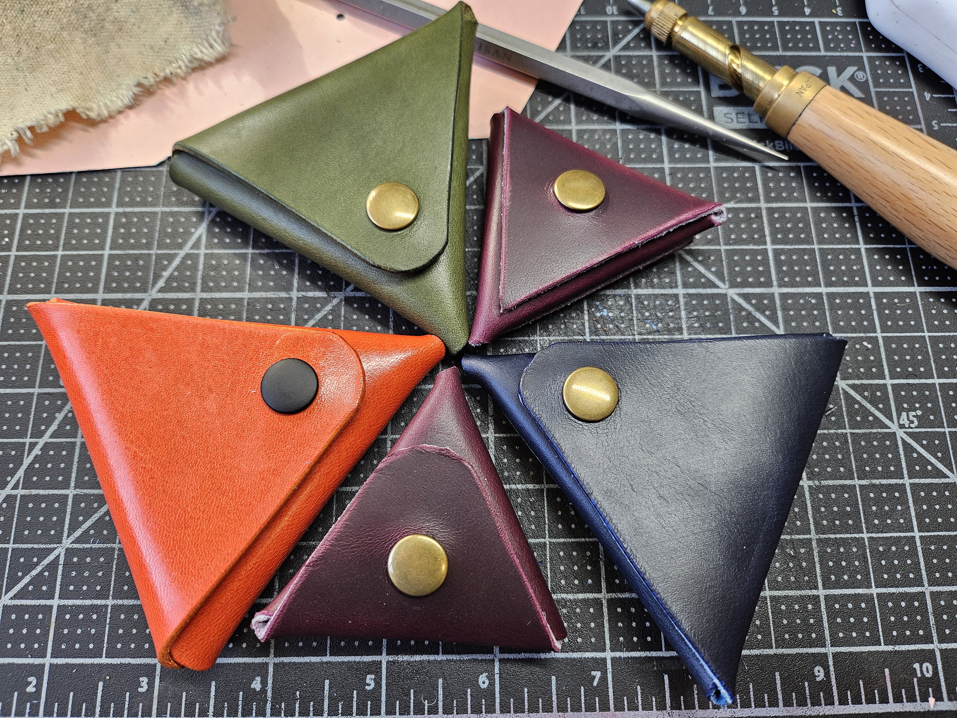 5 small triangular pouches made of leather in two sizes and various colors.