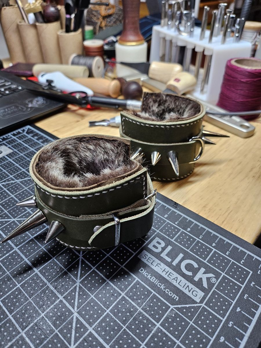 Olive green leather cuffs with silver spikes and a shearling lining.