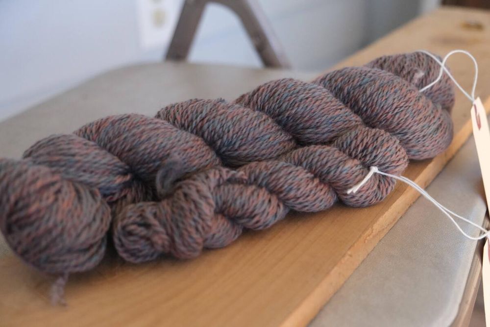 2 skeins, one large and one small, of a heathered grey yarn with hints of blue and orange in about a sport or DK weight.
