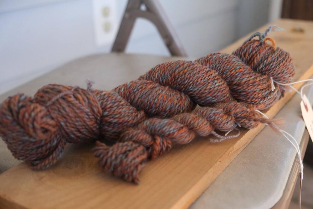 2 skeins, one large and one small, of a heathered orange yarn with hints of blue in about a DK or worsted weight.