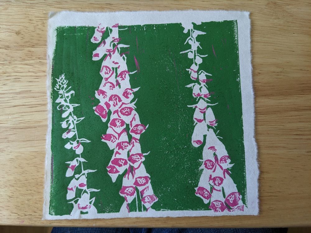 A print of a cluster of foxgloves. The background is inked in green, with negative space and pink details making up the foxgloves.
