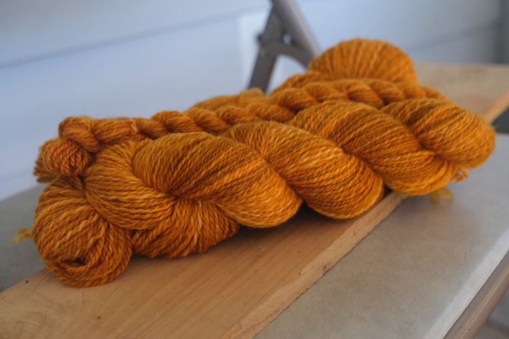 3 skeins, one small and two large, of a rich golden-orange handspun with light tonal effects, in about a DK weight