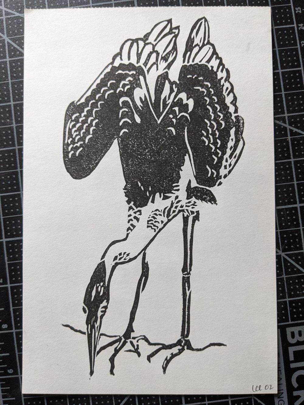 A print in black ink of a great blue heron, leaning downwards so that eir beak is level with eir feet.