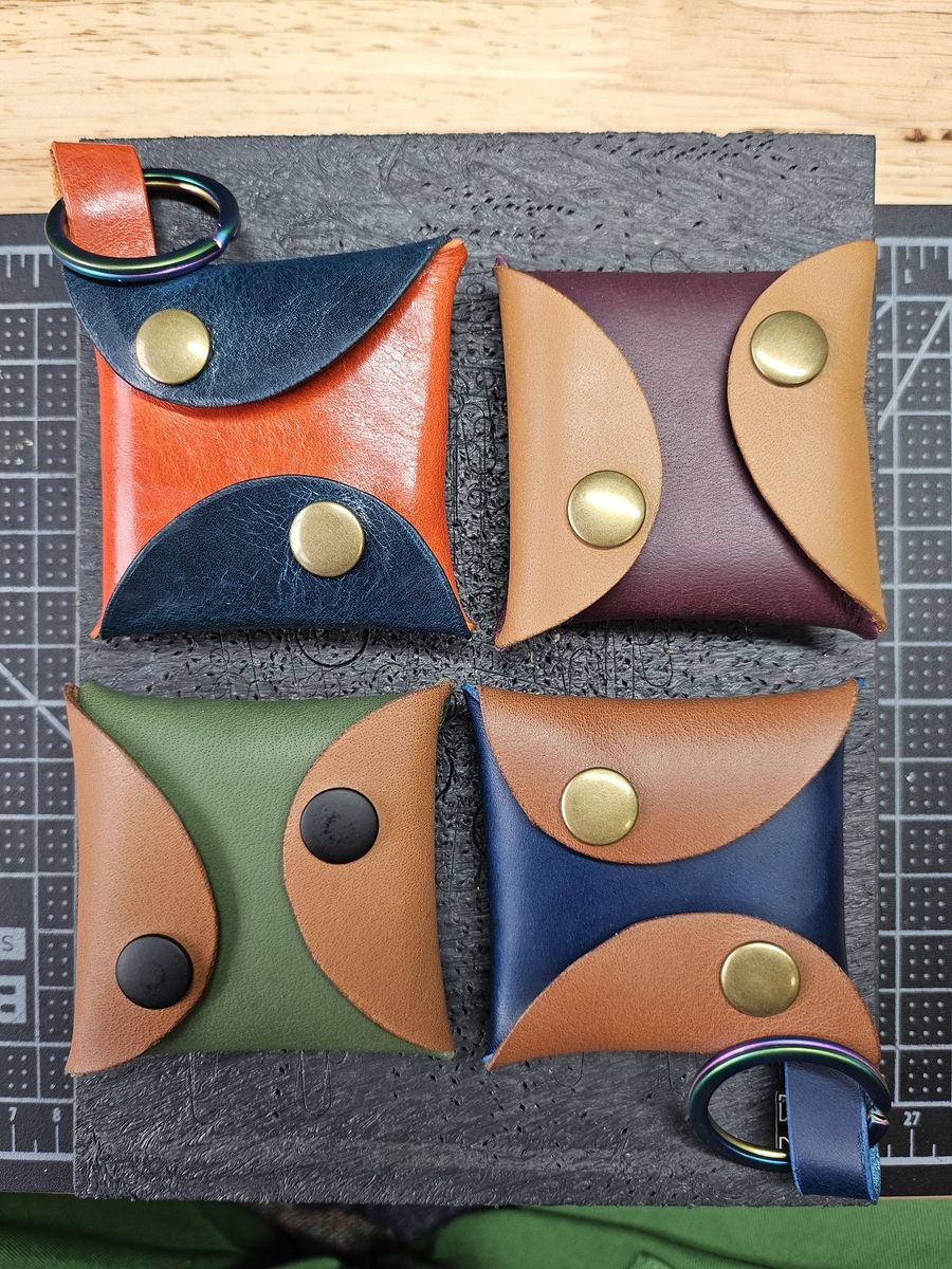 4 square pouches that close with snaps. 2 have loops that attach keyrings. They are in various colors of leather.