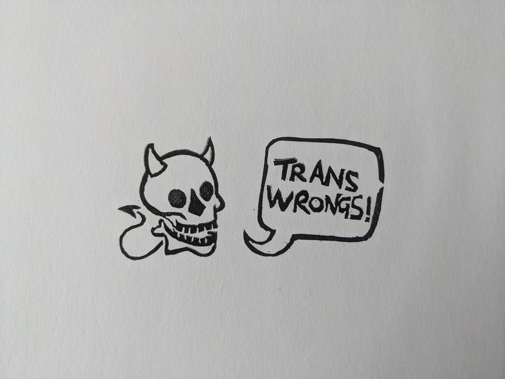 A smiling skull with devil horns and a little spiked tail, and a speech bubble reading 'trans wrongs!'